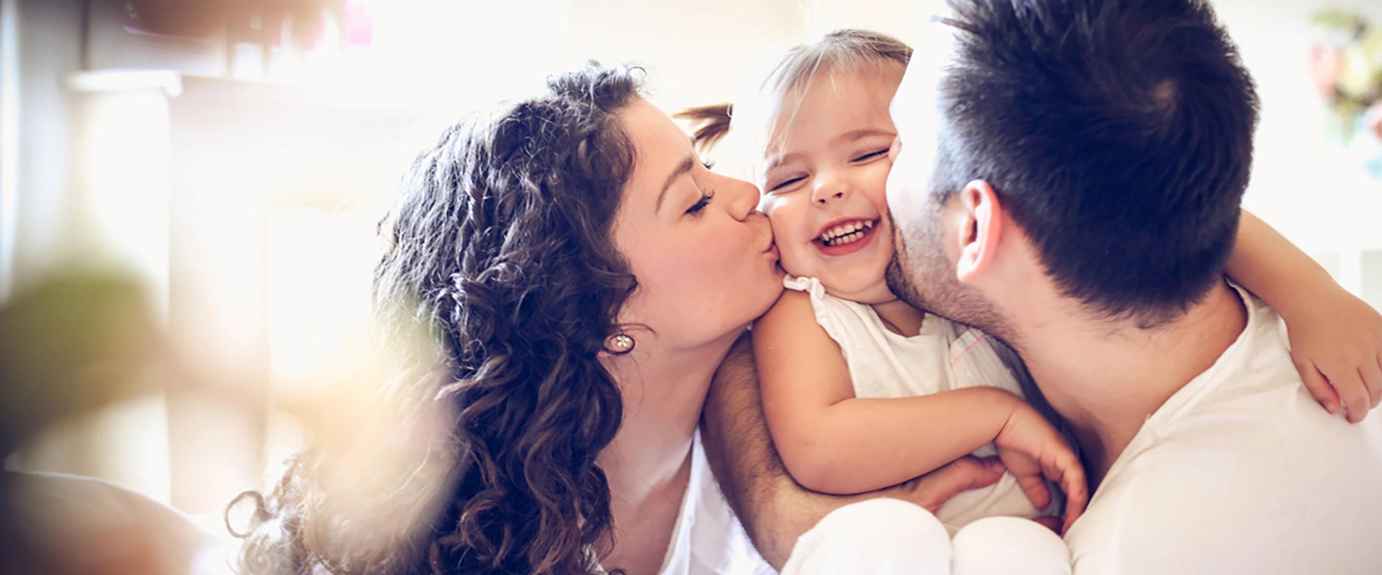 Couple kissing a baby on the cheeks